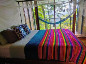 Un dormitorio con una cama con una manta de colores. en Selva Madre Eco-Sanctuary, en Cahuita