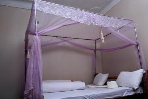 1 dormitorio con cama con dosel y sábanas blancas en Sipi Guest House, en Kapchorwa