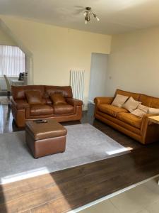 una sala de estar con 2 sofás de cuero y un taburete en Greenwood en Mánchester