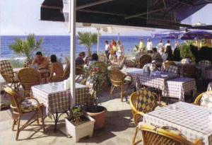 a group of people sitting at a restaurant on the beach at Sergent Hotel in Kuşadası