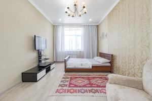 a living room with a bed and a television at Светлая квартира in Zaozërnyy