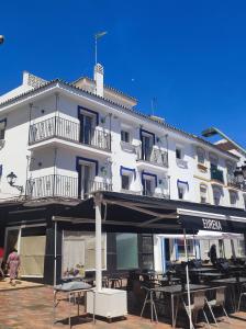 - un grand bâtiment blanc avec des tables devant dans l'établissement Coqueto apto en centro histórico, à Marbella