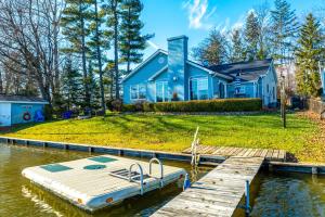 une maison bleue avec un quai et un bateau sur l'eau dans l'établissement Lakefront Paw Paw Cottage with Boats and 2 Docks!, à Paw Paw