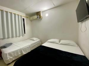 two beds in a room with a tv on the wall at Apartamento cerca del aeropuerto in Cartagena de Indias