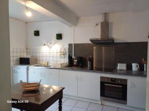 a kitchen with white cabinets and a table in it at La maison d'Amelie in Montesquieu-Volvestre