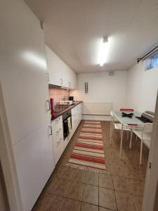 a kitchen with white cabinets and a table with a rug at Centrala Tanumshede in Tanumshede