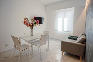 una mesa de comedor blanca con sillas y un jarrón con flores en AR Palace Hotel - Palermo en Isola delle Femmine