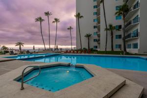 a swimming pool with palm trees and a building at Beach Paradise Luxury Views Here in Rosarito