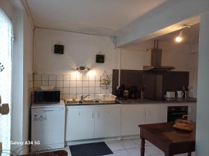 a kitchen with white cabinets and a sink and a table at La maison d'Amelie in Montesquieu-Volvestre +5 photos