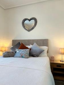 a bed with pillows and a heart sign on the wall at Abbey House B & B in Penrith