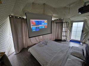 1 dormitorio con cama y pantalla de proyección en Glamping Georgia Krikhi en Ambrolauri