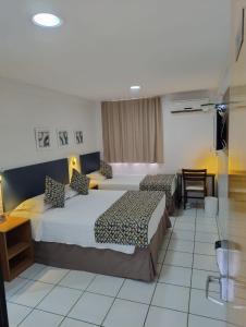 ein Hotelzimmer mit 2 Betten, einem Tisch und Stühlen in der Unterkunft Villa Park Hotel Fortaleza - antes Hotel Villamaris in Fortaleza