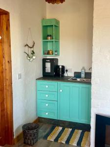 a kitchen with a blue cabinet and a microwave at Clarefornia Stone Shed in Lahinch +26 photos