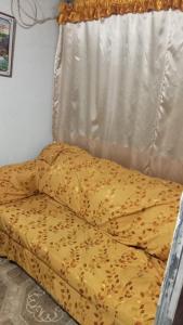 - un lit avec une couette jaune devant une fenêtre dans l'établissement HABITACIONES ISABEL, à Lima