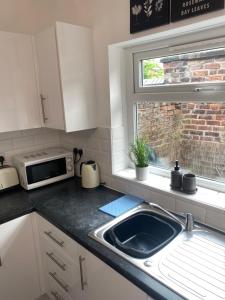 a kitchen with a sink and a microwave at Modern Manchester home, Free parking & near city centre in Manchester