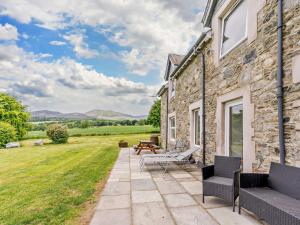 une maison en pierre avec une terrasse et une pelouse dans l'établissement 3 Bed in Pitlochry 59677, à Pitlochry
