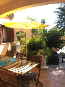- une table en bois avec un parasol sur la terrasse dans l'établissement Villa paradis, à Fréjus