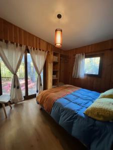 Un dormitorio con una cama azul y una ventana en Cabañas Alegria Caburgua Pucon, en Caburgua