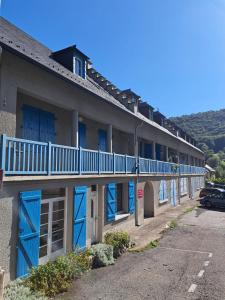 a building with blue doors and a parking lot at Grand appartement en RDC Vallée de Campan in Campan