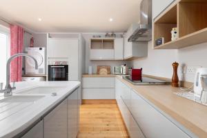 uma cozinha com armários brancos e piso em madeira em Holbrook house em Cambridge