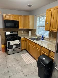 uma cozinha com armários de madeira e um forno com placa de fogão em Fidelia Room B Queen Bed Near EWR Airport and Penn Station em Irvington