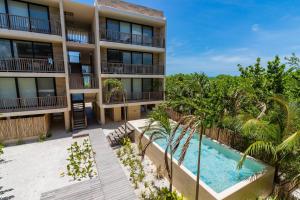 an apartment building with a swimming pool and palm trees at Penthouse Con Alberca Privada Y Hermosas Vistas Al Mar - C301 in Holbox Island