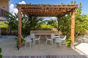 una mesa de picnic y sillas bajo una pérgola de madera en Pool View Loft Steps From The Ocean - Punta Cocos en Holbox Island