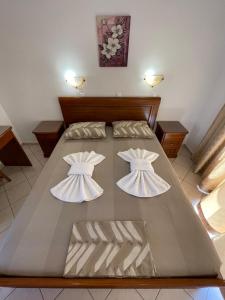 a bedroom with a large bed with two white sheets at Avra Studios in Lefkos Karpathou
