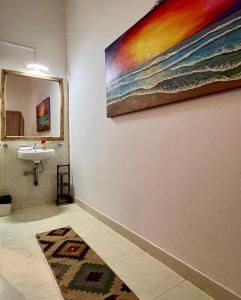 亞蘭博的住宿－Double V Arambol，一间带水槽的浴室和墙上的绘画