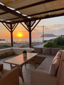 a patio with a table and a couch and the sunset at Avra Studios in Lefkos Karpathou +33 photos
