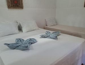 a white bed with two blue flowers on it at Estresse Zero in Atins