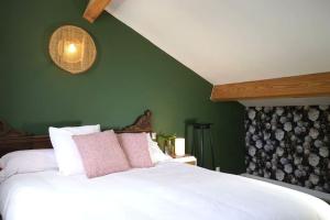 une chambre avec un lit blanc avec un mur vert dans l'établissement Maison tout confort avec Piscine, à Saint-Martin-de-Londres