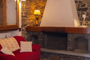 a living room with a stone fireplace with a red couch at Appartamento Rita in Asso