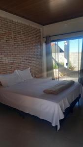 uma cama grande num quarto com uma parede de tijolos em Mangabeiras - Casa de Hóspedes em Alto Paraíso de Goiás