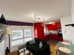 a living room with red cabinets and a black couch at Piso da Ulla in A Estrada