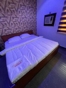 1 dormitorio con 1 cama grande y edredón blanco en Calawazobia Hotel, en Uyo