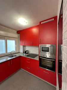a red kitchen with a sink and a microwave at Piso da Ulla in A Estrada +9 photos