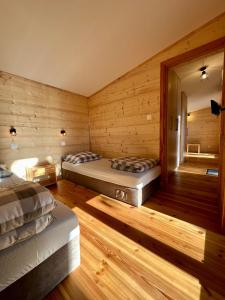 two beds in a room with wooden walls at Metropolis Domki in Sopot