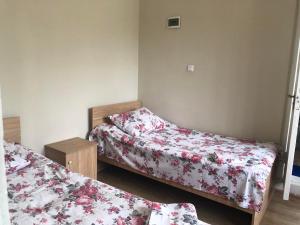 two beds in a room with floral sheets at Отел Нана in K'obulet'i
