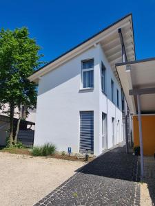 un edificio blanco con un árbol delante en Apartment am Rohrbach, en Friedrichshafen
