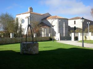 a large white building with a church in the background at Alojamiento Rural La Henera in San Juan de Ortega