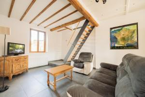a living room with a couch and a tv at Gîte de la Louvière - maison de campagne in Grandpré