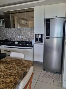 a kitchen with white cabinets and a stainless steel refrigerator at Terraço do Atlântico in Fortaleza