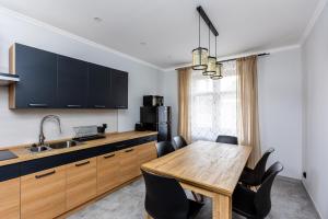 a kitchen with a wooden table and black cabinets at Noclegi na Wspólnej 