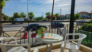 a table and chairs on a balcony with a view of a street at Polichrono Cosy Summer House in Polykhrono