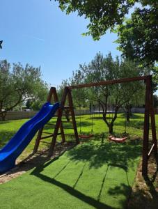 een speeltuin met een blauwe glijbaan in een park bij VILLA ANITA in Sveti Filip i Jakov