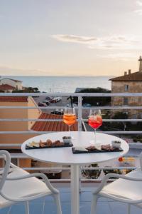 dos copas de vino sentadas en una mesa en un balcón en Hotel Nina en Marina di Bibbona