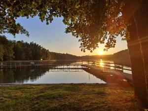a dock on a lake with the sun setting at Domki nad jeziorem in Przechlewo