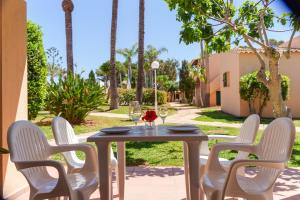 una mesa y sillas en un patio con palmeras en Cal Xoc - Apartamento paradisíaco junto al mar, en Son Xoriguer