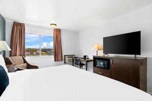 a hotel room with a bed and a flat screen tv at Red Lion Inn & Suites Yakima in Yakima